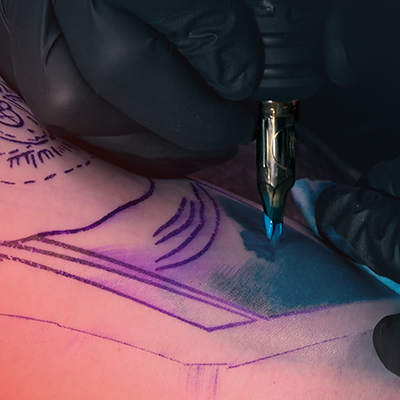 Un primo piano di una persona che riceve una sfumatura blu nel proprio tatuaggio.